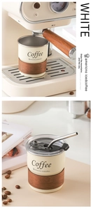 Detail of cream stainless steel coffee cup with wood grain heat sleeve and metal straw