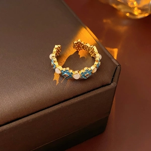 Detailed macro of vintage 18k gold plated enamel ring with blue floral and pearl accents