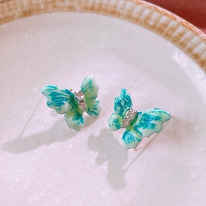 Macro shot of butterfly stud earrings with green gradient enamel and sparkling crystals