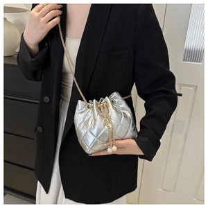 Detail of silver quilted bucket bag with golden chain and pearl drawstring charms