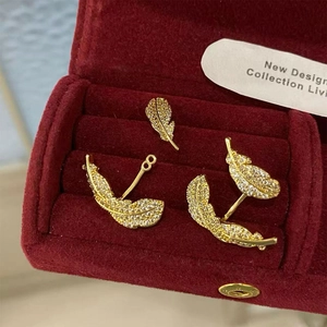 Close-up of gold-plated feather earrings with micro-set zircon on red velvet box