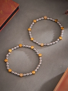 Detailed macro view of silver beaded elastic bracelets with gold zircon flower charms