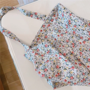 Close-up of green floral cotton tote bag with red and yellow flowers on white surface