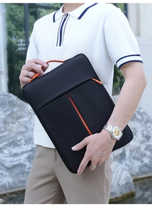 Detail of slim laptop bag with reinforced handle and orange accents in outdoor use