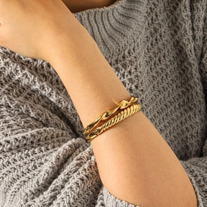 Gros plan de bracelets torsadés plaqués or 18 carats sur mannequin avec fond tricot