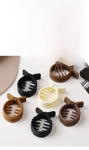 Detailed view of matte round claw clips in neutral tones like black, caramel, and cream