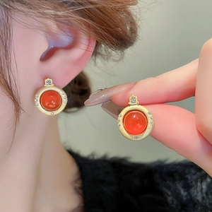 Boucles d'oreilles vintage dorées avec agate rouge et halo de cristaux sur le modèle