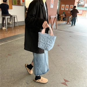 Detailed shot of light blue quilted tote with pink handles shown in outdoor lifestyle setting