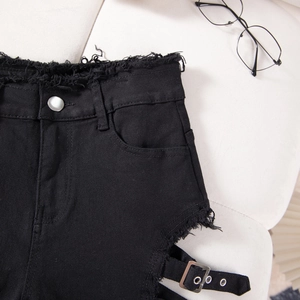 Detalle de pantalones cortos de mezclilla negra con bordes deshilachados y hebilla