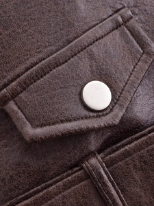 Detailed view of dark brown PU leather jacket featuring fine texture and metal button