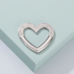 Macro detail of a silver heart pendant with side-set sparkling cubic zirconia on a cube