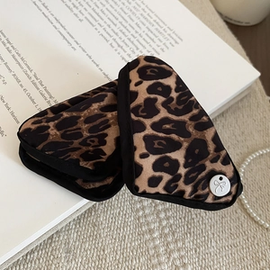 Macro view of leopard print fabric accessories with bow-engraved metal button on a vintage book