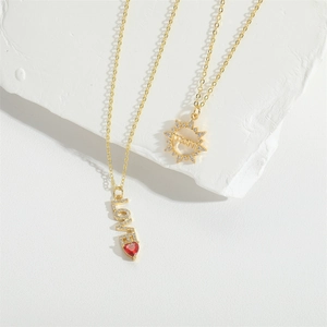 Gold-toned layered necklace with LOVE pendant, red heart gem, and sun-shaped mom charm