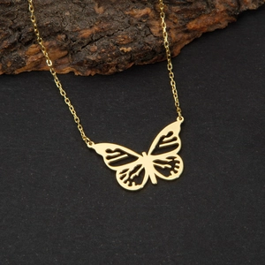 Gros plan du pendentif papillon plaqué or 18 carats ajouré sur fond de pierre