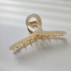 Elegant large pearlescent hair claw clip with golden metal spring on white background
