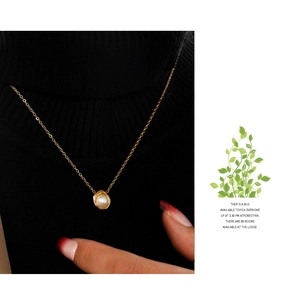 Detail of elegant gold necklace with pearl pendant on a black turtleneck sweater