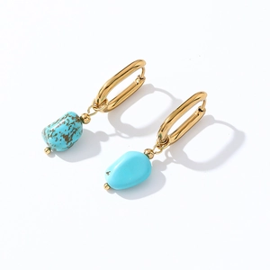 Macro detail of gold earrings featuring irregular natural turquoise stone pendants