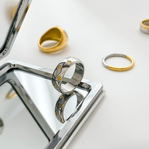Macro detail of silver titanium steel ring featuring gold star accents and mirror reflections