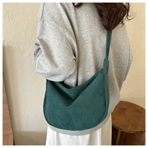 Détail du sac à bandoulière en velours côtelé vert foncé avec texture rayée et style hobo