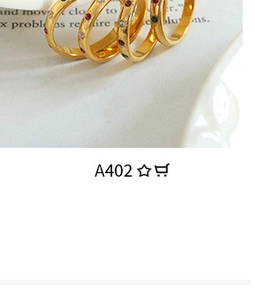 Close-up of four gold-plated rings with colorful inlaid stones on a book background