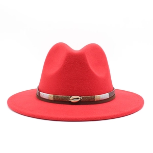 Detail of red wool fedora hat featuring a brown leather band and golden shell buckle