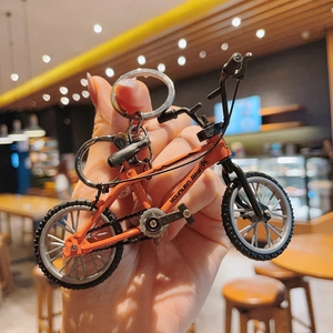 Detailed close-up of a bright orange mini mountain bike keychain with a silver metal ring