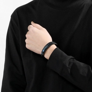 Detail of a men's multi-layer black braided leather bracelet with a blue metal accent