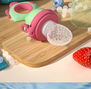 Close-up of pink and green dinosaur baby fruit feeder with food-grade silicone teat