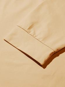 Detailed close-up of the beige knitted cotton sleeve cuff with high-density stitching