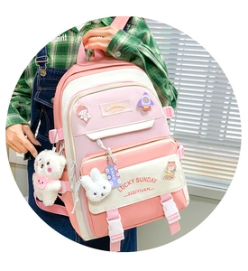Close-up of pink and beige backpack featuring cute cartoon badges and plush charms
