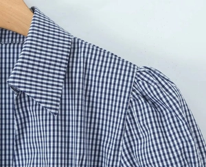 Detail of the blue and white checkered shirt neckline and pleated shoulder tailoring