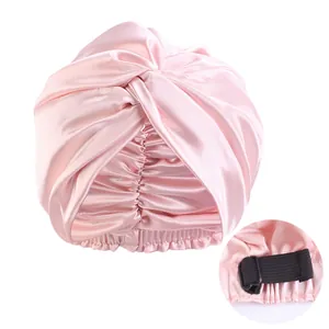 Pink satin sleep cap featuring adjustable elastic strap buckle and twisted knot design