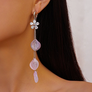 Detailed view of long floral resin earrings with pink petals and zircon studs on model