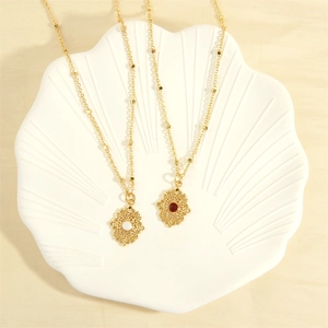 Detail of vintage 18K gold plated necklaces with red and white gemstone pendants