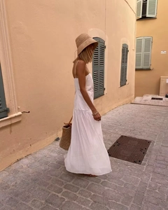 Detail of a white pleated maxi dress with spaghetti straps in a vacation street setting