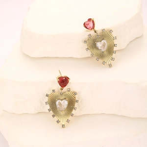 Gold plated heart drop earrings with red and white zircons on a minimalist stone display