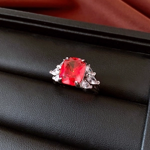 Macro shot of a large rectangular red zircon stone on a silver ring with side marquise accents