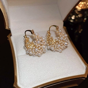 Close-up of gold C-shaped hoop earrings with white pearls in a velvet jewelry box