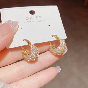 Macro detail of gold huggie earrings featuring micro-pave clear cubic zirconia crystals