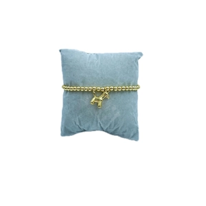 Golden beaded unicorn bracelet on blue velvet cushion with mirror-like metallic finish
