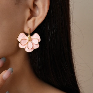 Macro shot of pink enamel ginkgo flower earrings with gold plating on a model ear