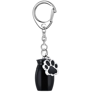 Detail of black cylinder pet cremation urn keychain with silver paw print charm