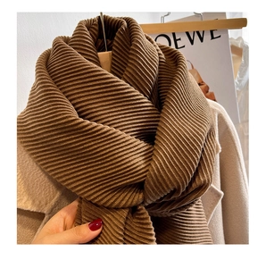 Detail of heavy brown rib-knit scarf texture draped on an elegant wool coat for winter