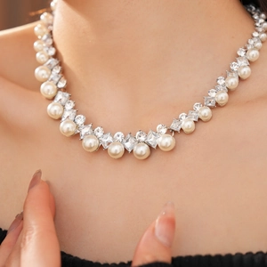 Detail of elegant pearl necklace with diamond accents worn by a model in soft lighting