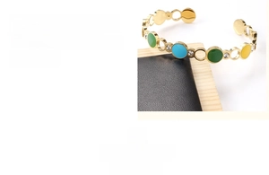 Detail of gold-plated stainless steel C-shape bracelet with colorful enamel and zircons
