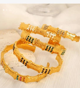 Detail of bamboo joint gold bangle with colorful stones and pearls on elegant fabric