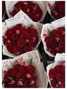 Detail of premium red velvet roses and pink tulips in elegant patterned wrapping