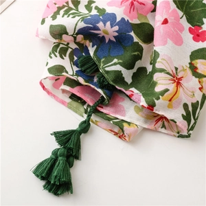 Close-up of floral print cotton linen scarf with dark green tassel pendant details