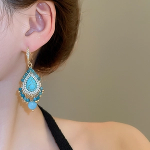 Detail view of bohemian turquoise drop earrings with fringe and sparkling rhinestones