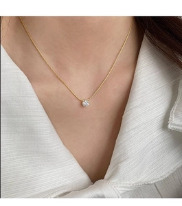 Elegant gold zircon necklace with round pendant worn on a female model collarbone